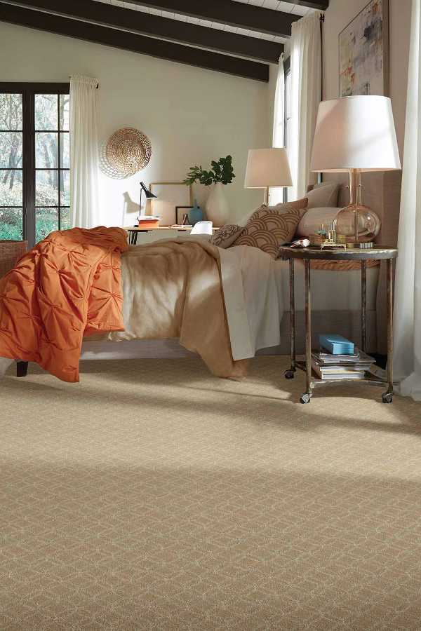 transitional bedroom with beige carpet and orange bedspread